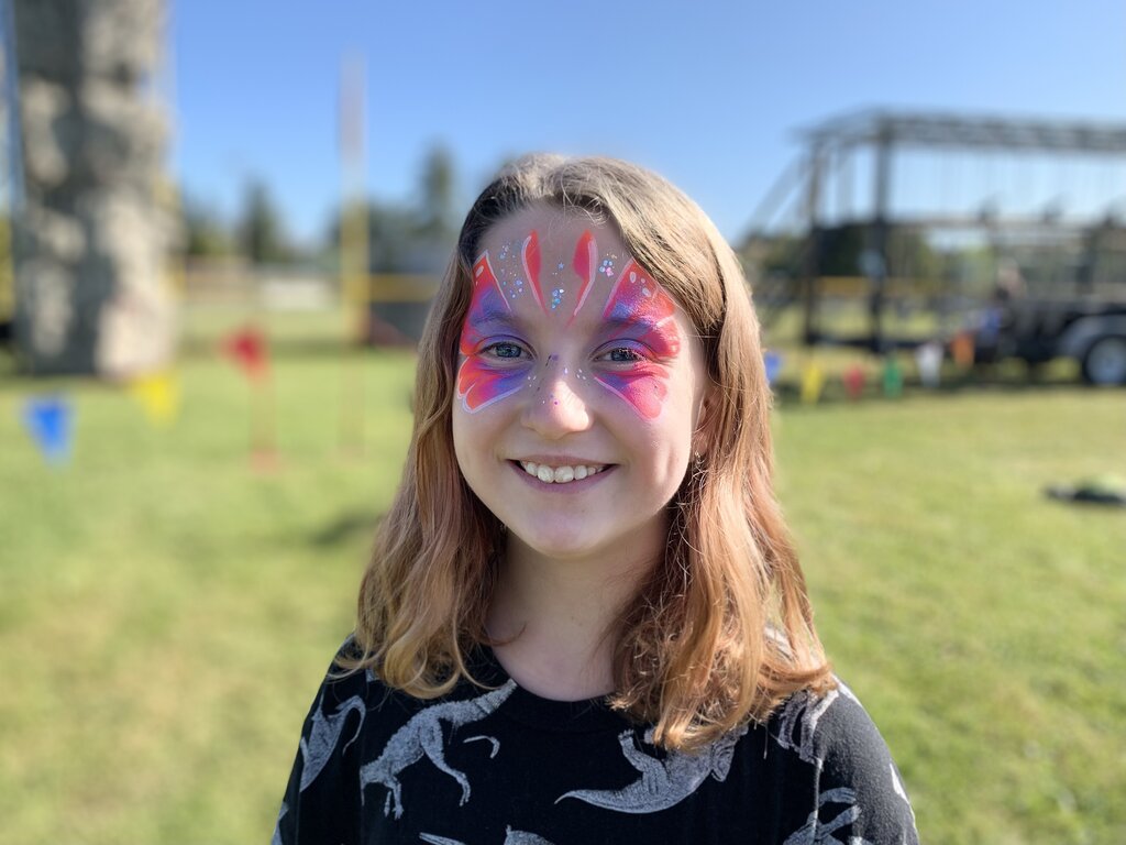 Happy child with pink and purple butterfly face painting with sparkles