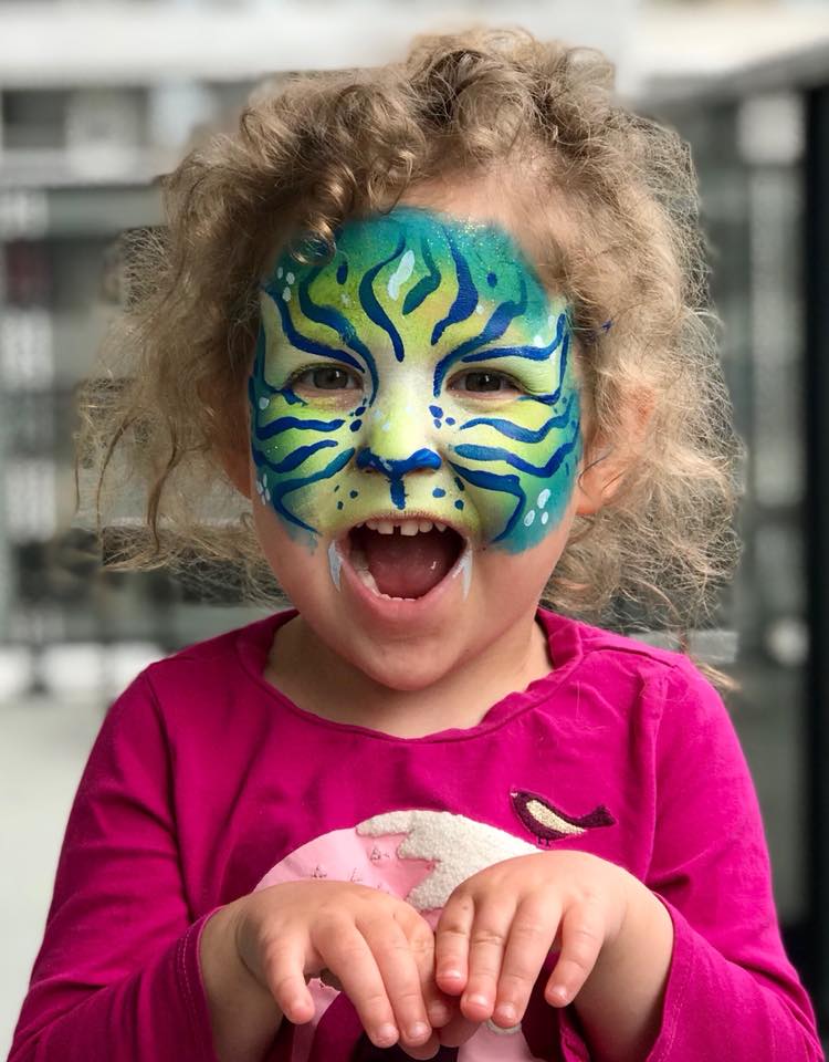 Child with detailed tiger face painting design at a festival